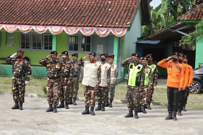 several men in uniform saluting at soing while people watch from the other side of the building