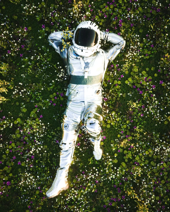 the man in a white suit is laying in a field of flowers
