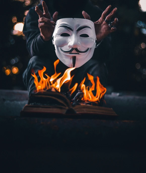 someone wearing a guy fawkett mask and holding a book