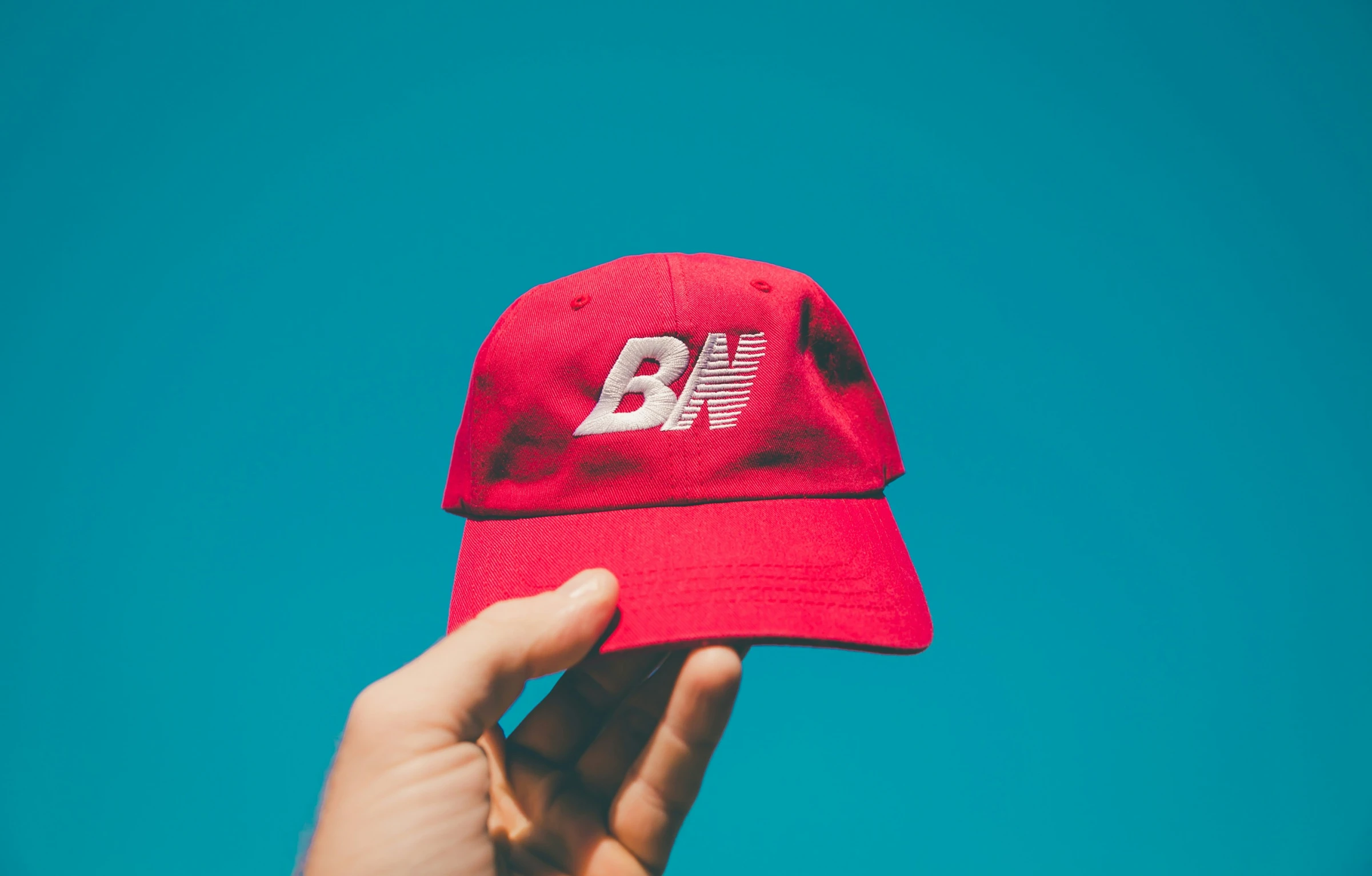 someone is holding their hat with the blue sky in the background