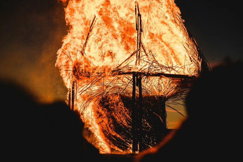 the silhouette of a ship on fire with bright orange flames