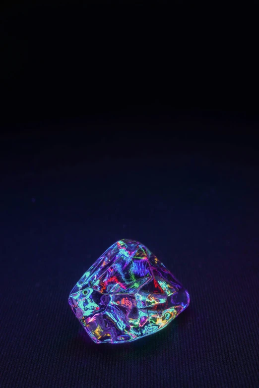 a single diamond with purple and red light in the dark