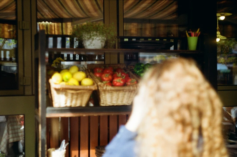 a woman looking at some produce behind glass doors