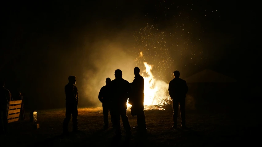 a group of people standing around a fire pit