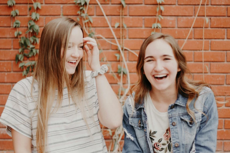 two girls laugh as they hold hands behind their backs