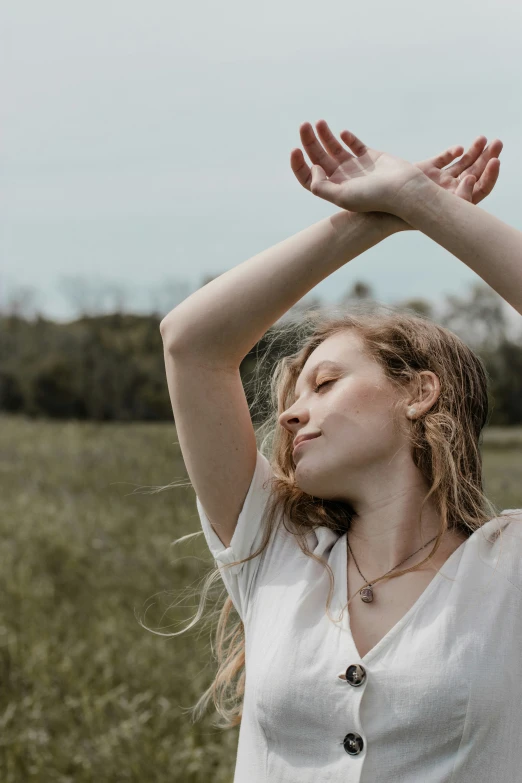 a woman sitting in a field stretching her hands