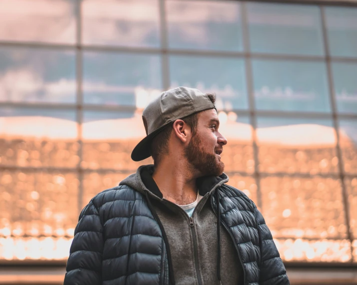 a man in a baseball hat looking out the window