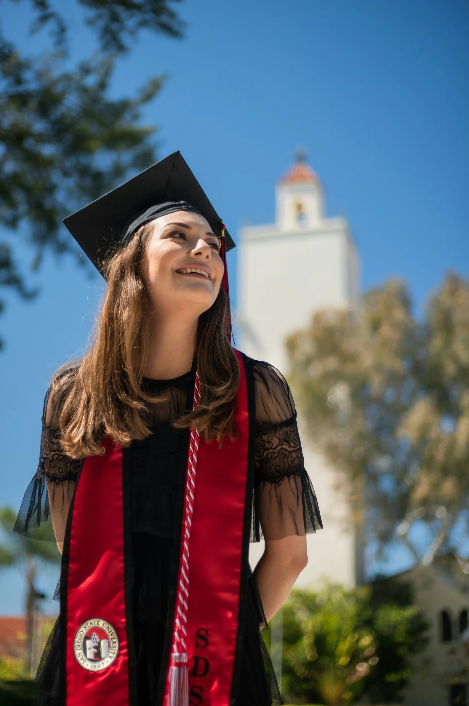 a female in a red graduation gown with a clock tower in the background