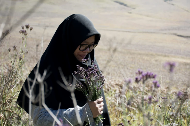 a woman is looking down while wearing a black head scarf