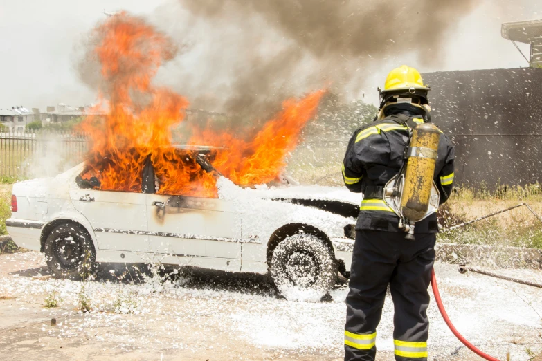 a man that is standing in front of a car on fire