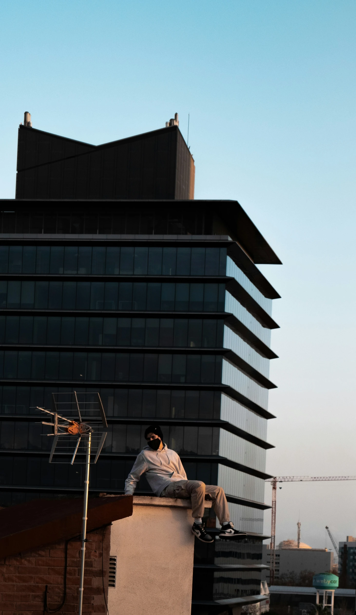 a man sits on top of a building with his skateboard in hand