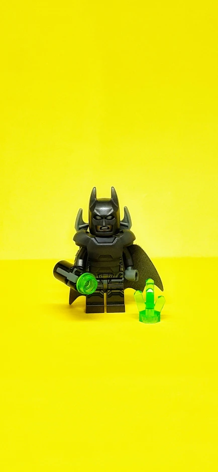 a lego batman with the bat standing next to it