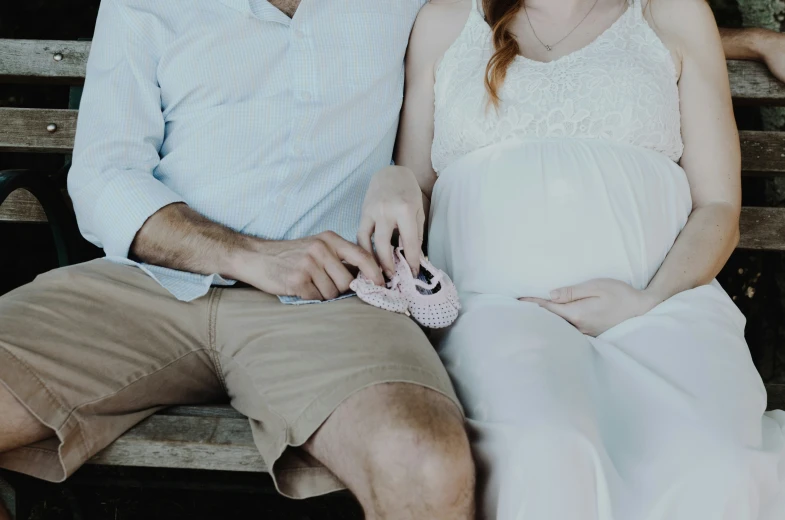 a pregnant woman on a bench is holding a purse