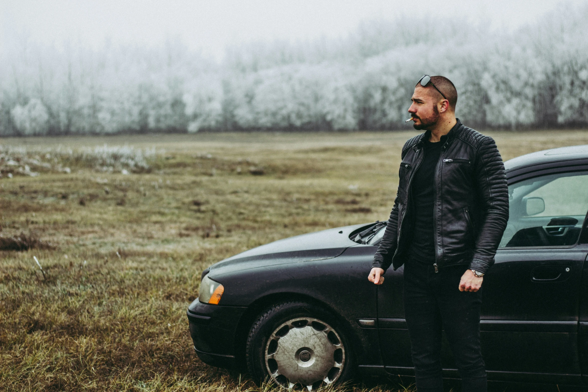 a man standing next to his car with a soccer ball in his hand