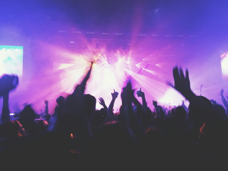 people waving their hands up while an auditorium audience watches