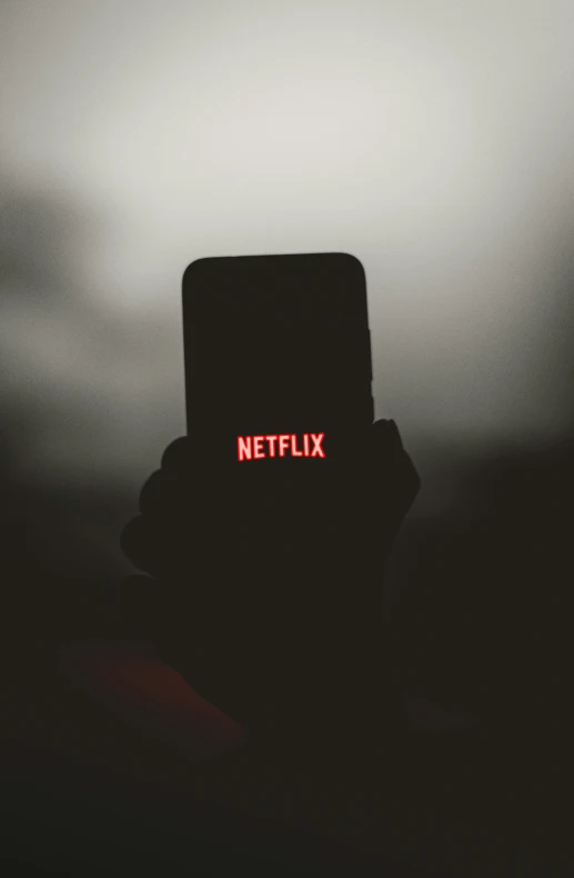 the dark red netflix streaming logo appears to be projected on a phone