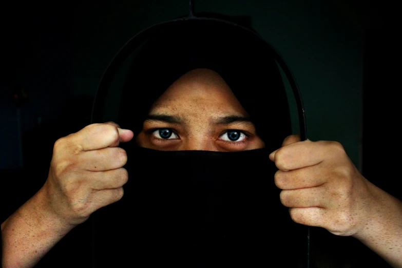 a woman with black cloth covering her head in the dark