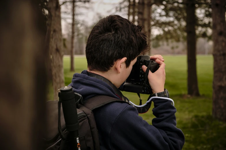 a boy is standing and looking through binoculars