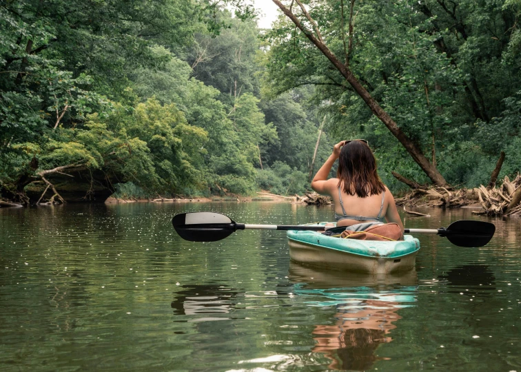 a man paddling a canoe down a small river