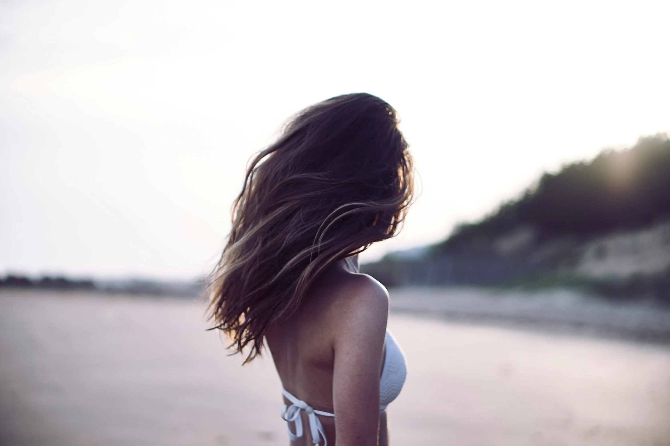 a woman with long hair walking on the beach