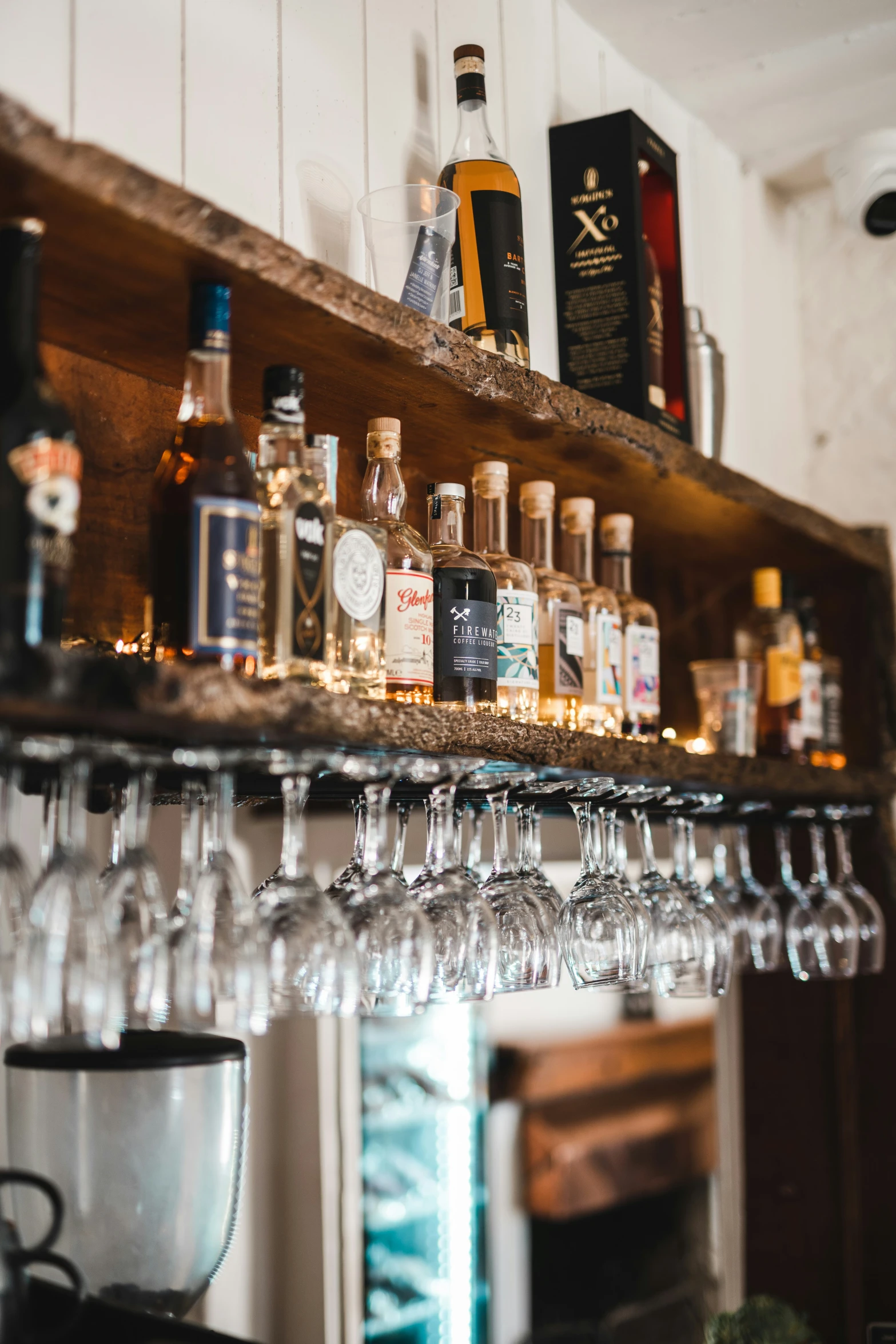 liquor glasses lined up on shelves of a bar