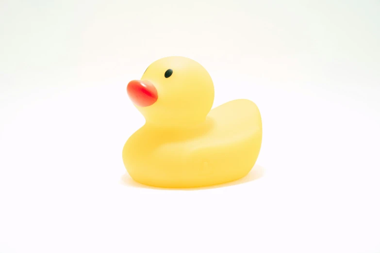 a yellow rubber duck toy sitting on a white surface