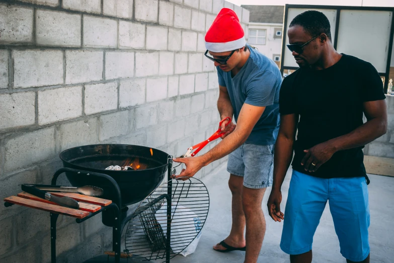 two men are standing near a grill with one holding an item