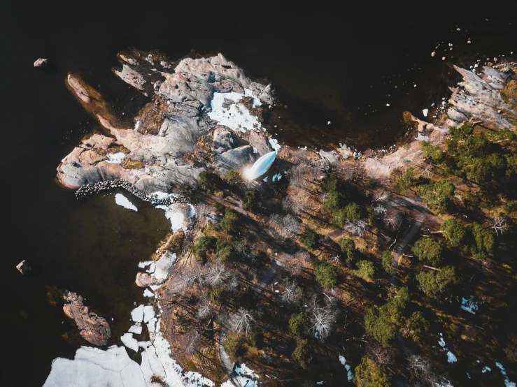 an aerial view of snow covered ground next to water