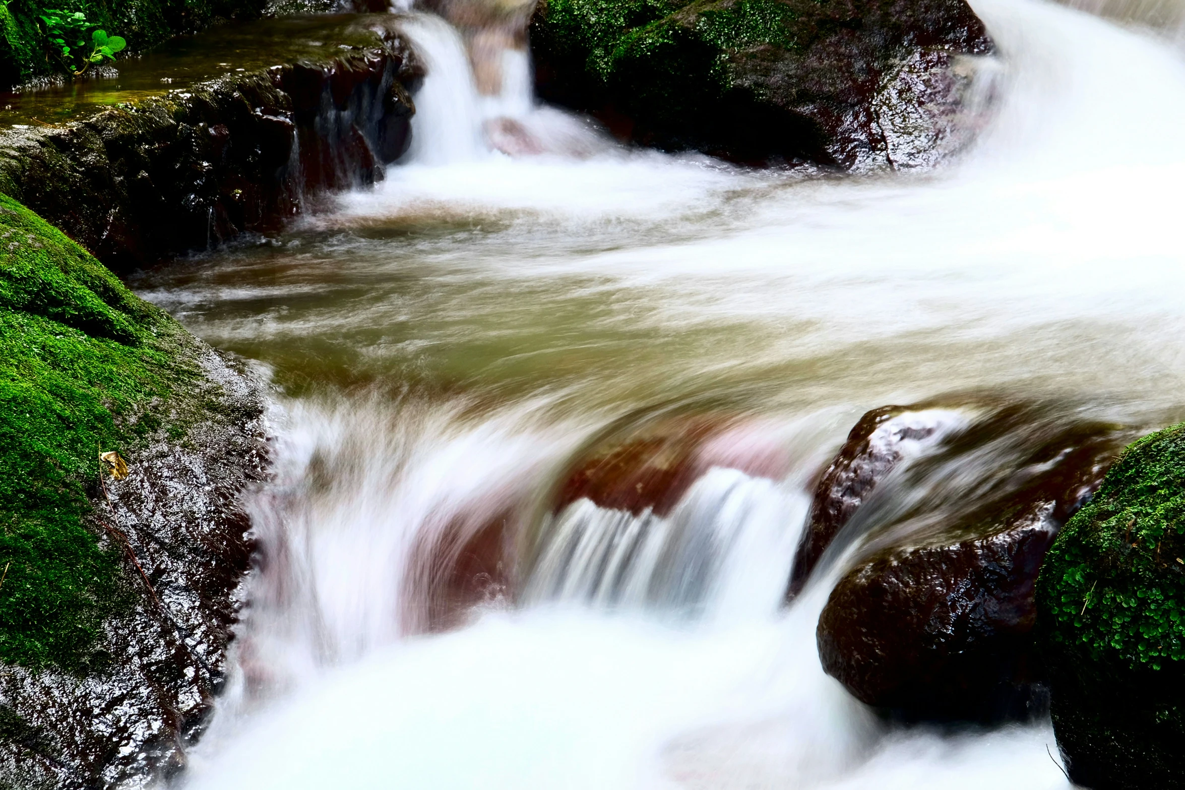 waterfall cascades near mossy rocks in stream