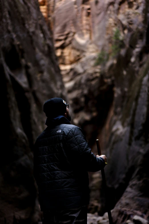 a man wearing a winter jacket standing at the bottom of a waterfall