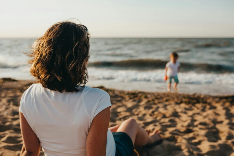 two women walking on the beach with one of them holding her hair