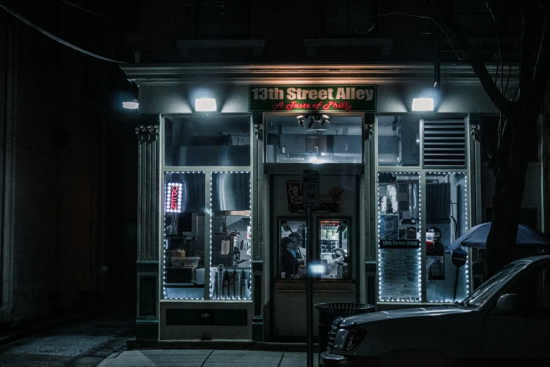 a dark street with lighted windows and cars parked outside at night