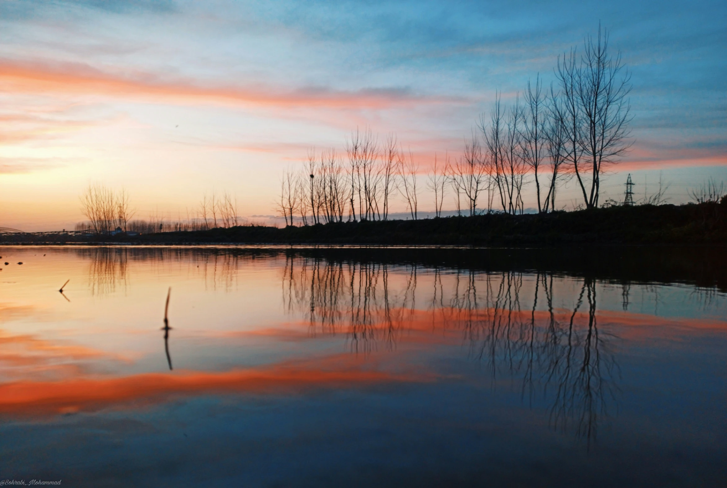 the sky is starting to reflect off of the still water