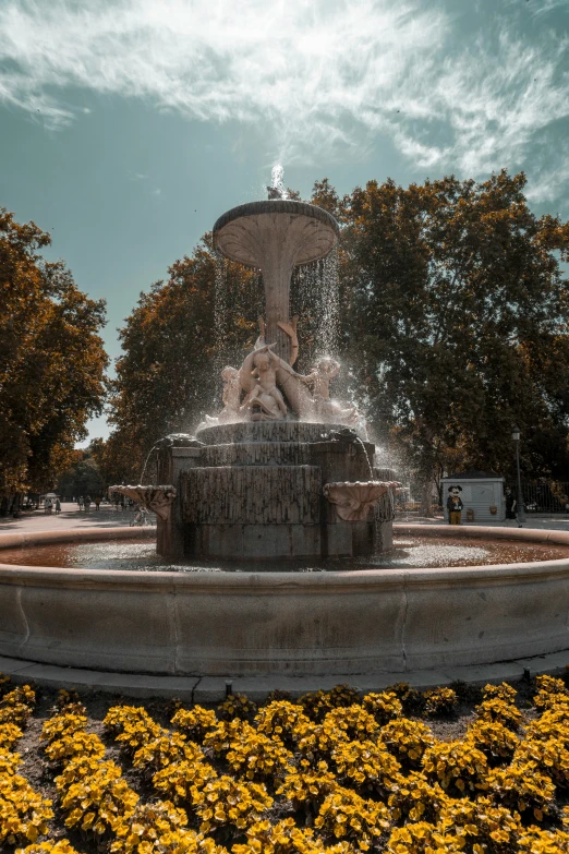 a large fountain surrounded by yellow flowers