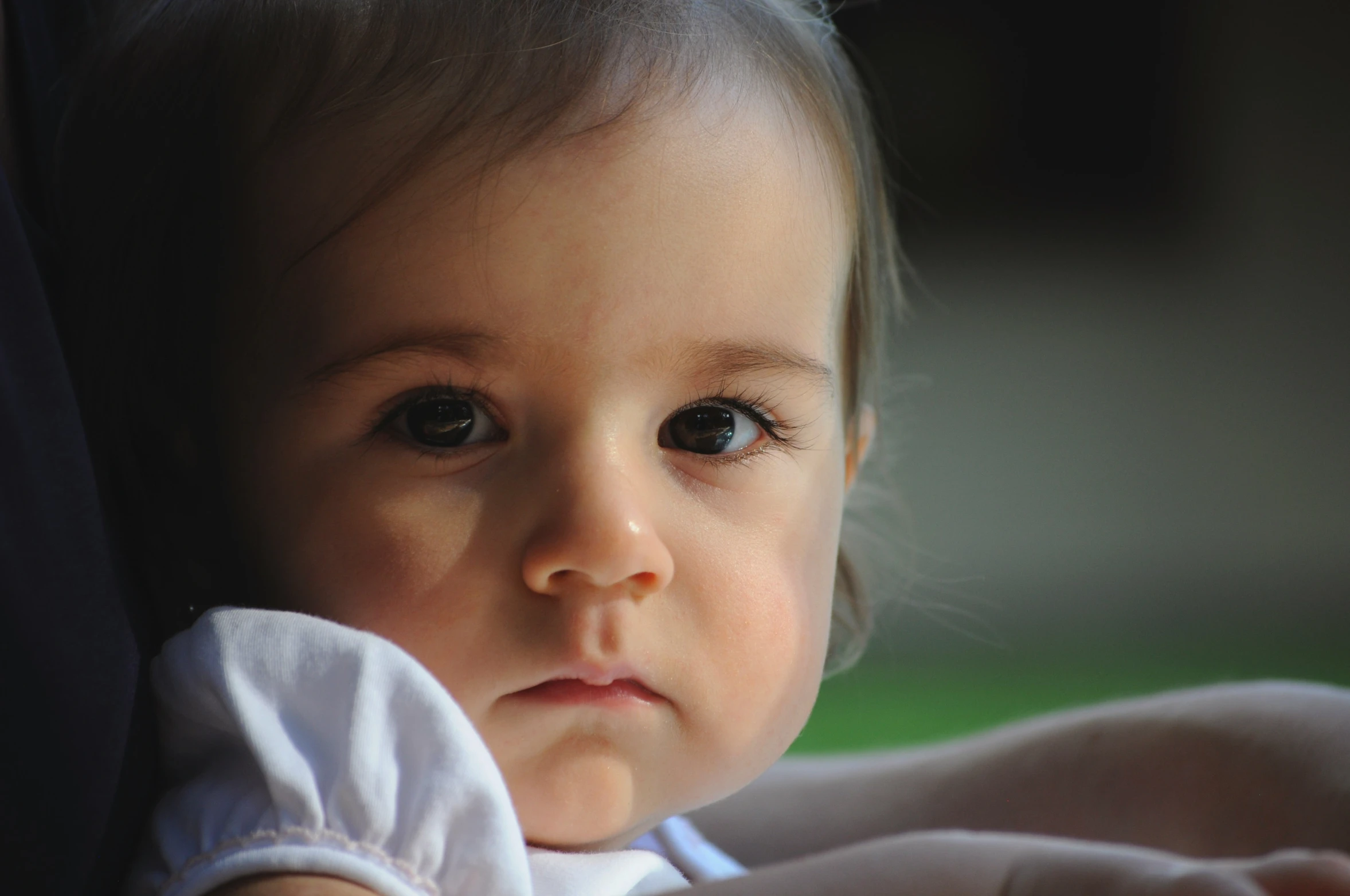 a small child wearing a white blouse looking at the camera