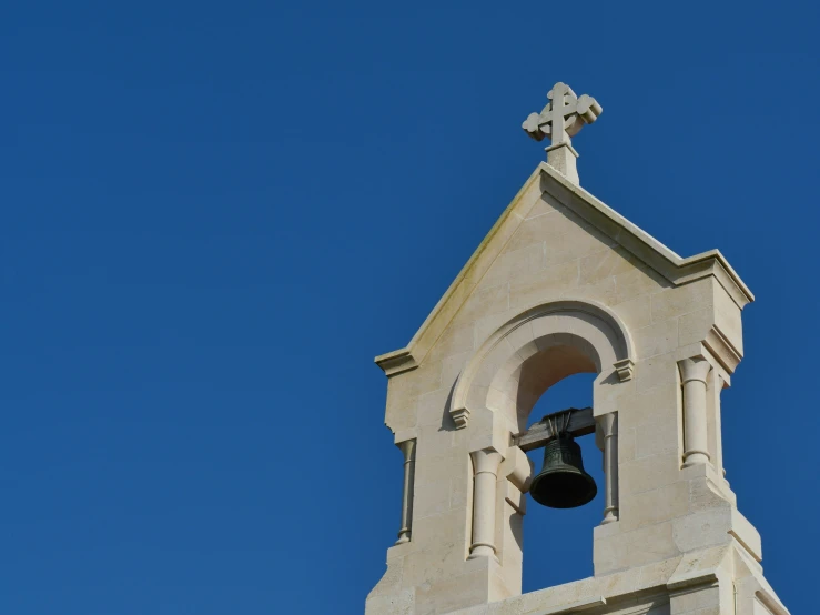 a bell tower has an arched window and a cross on it