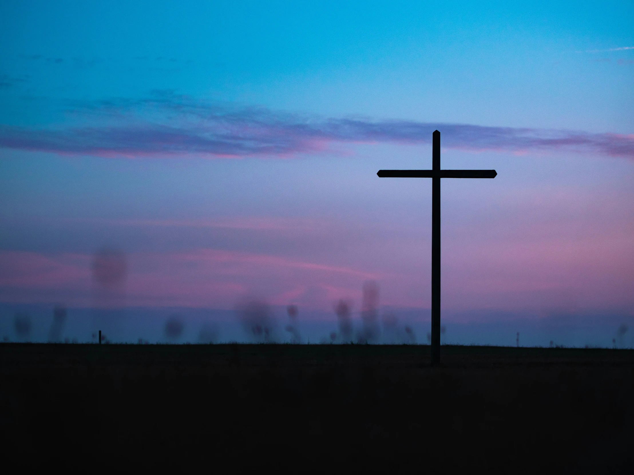 a silhouette of a cross on top of a hill