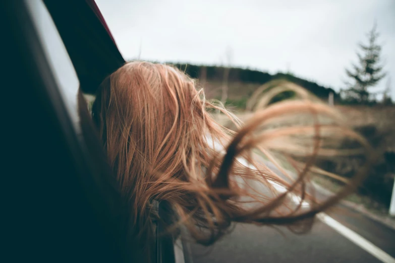 a girl with long hair leaning out of a car window