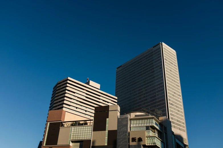 two tall buildings next to each other in front of a blue sky