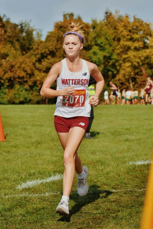 the girl running on the grass near cones