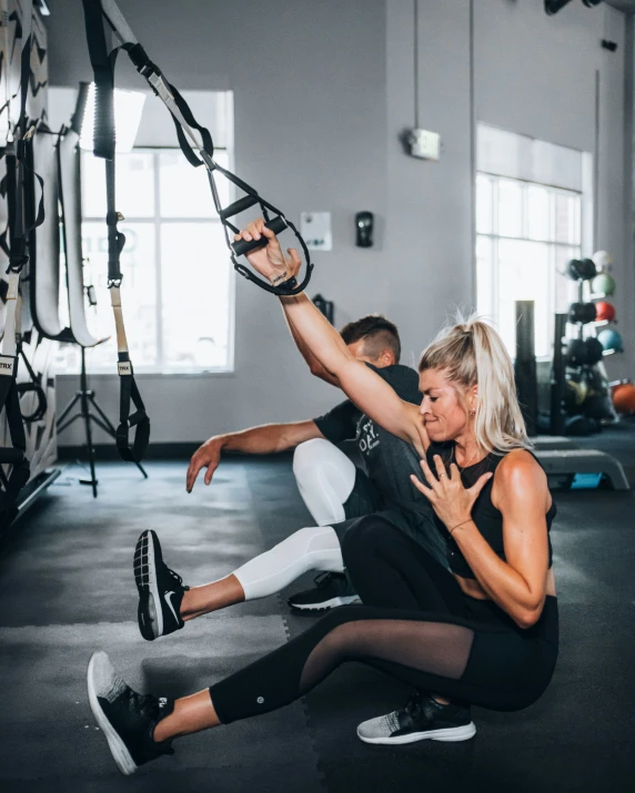 a woman doing pull ups with a man in the background