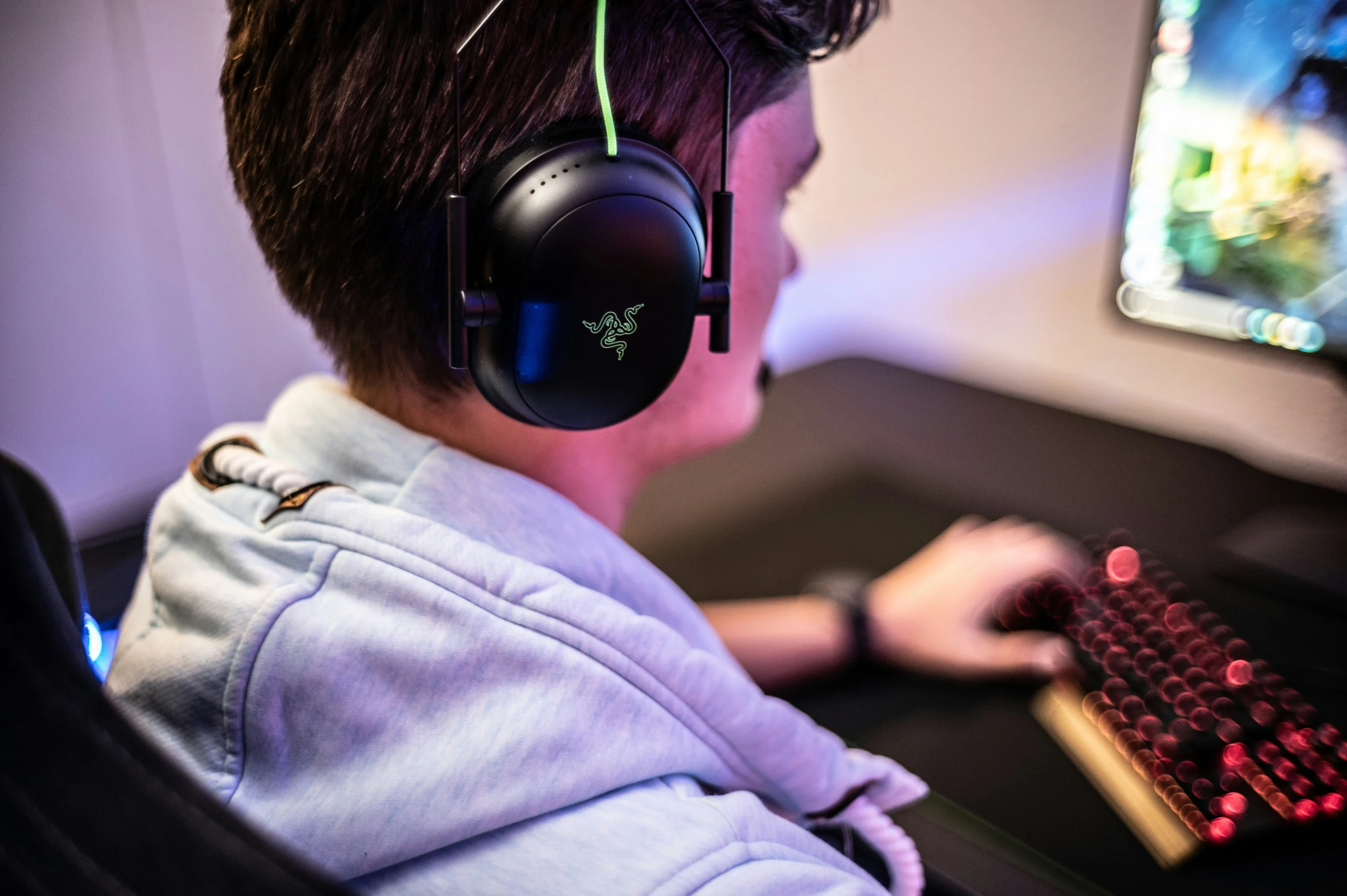 a young man in headphones sitting in front of a computer
