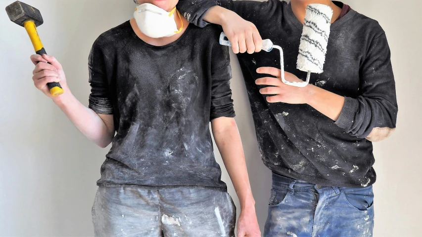 two young people stand together with a hammer and plaster in their mouths