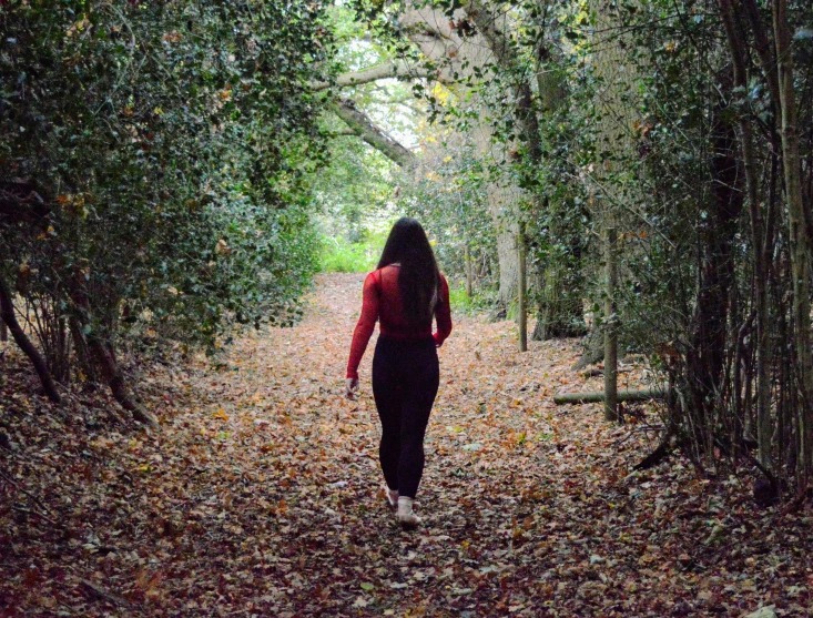 the woman walks through the woods carrying an umbrella