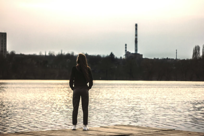 a girl standing on a wooden dock looking out at the water