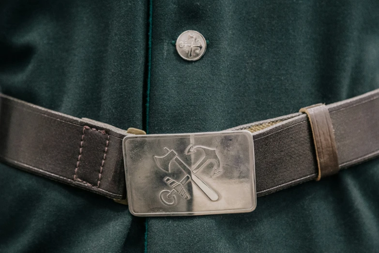 an odd badge on a belt with a coat in the background