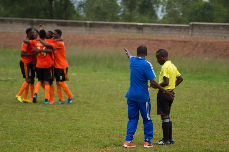 a soccer team huddled around an official in a field