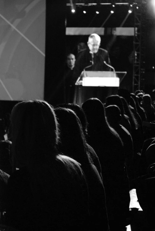 a black and white po of a speaker standing in front of an audience