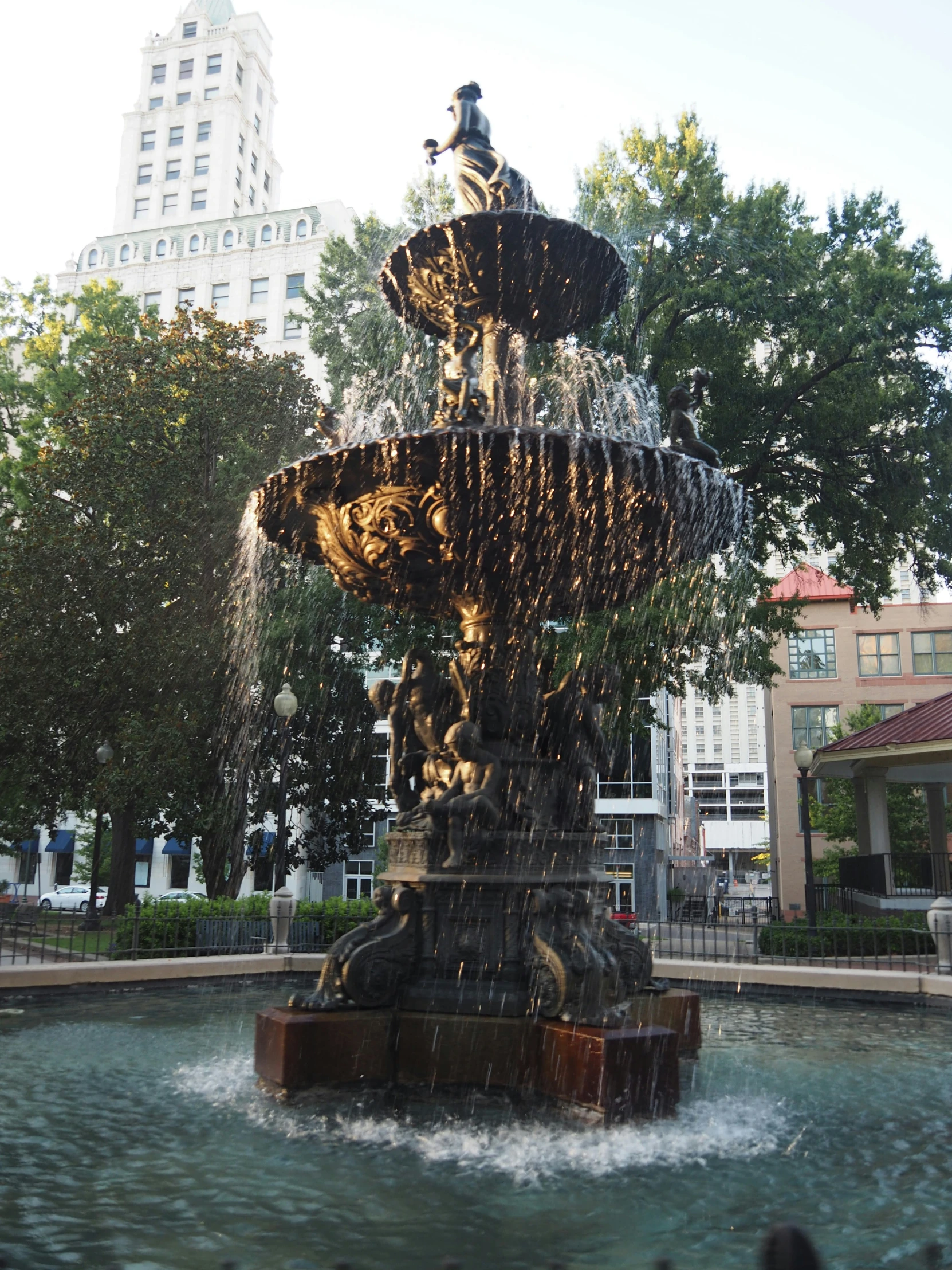 an outdoor fountain with some people and trees