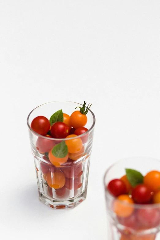 a glass filled with fruits sitting next to a small bowl